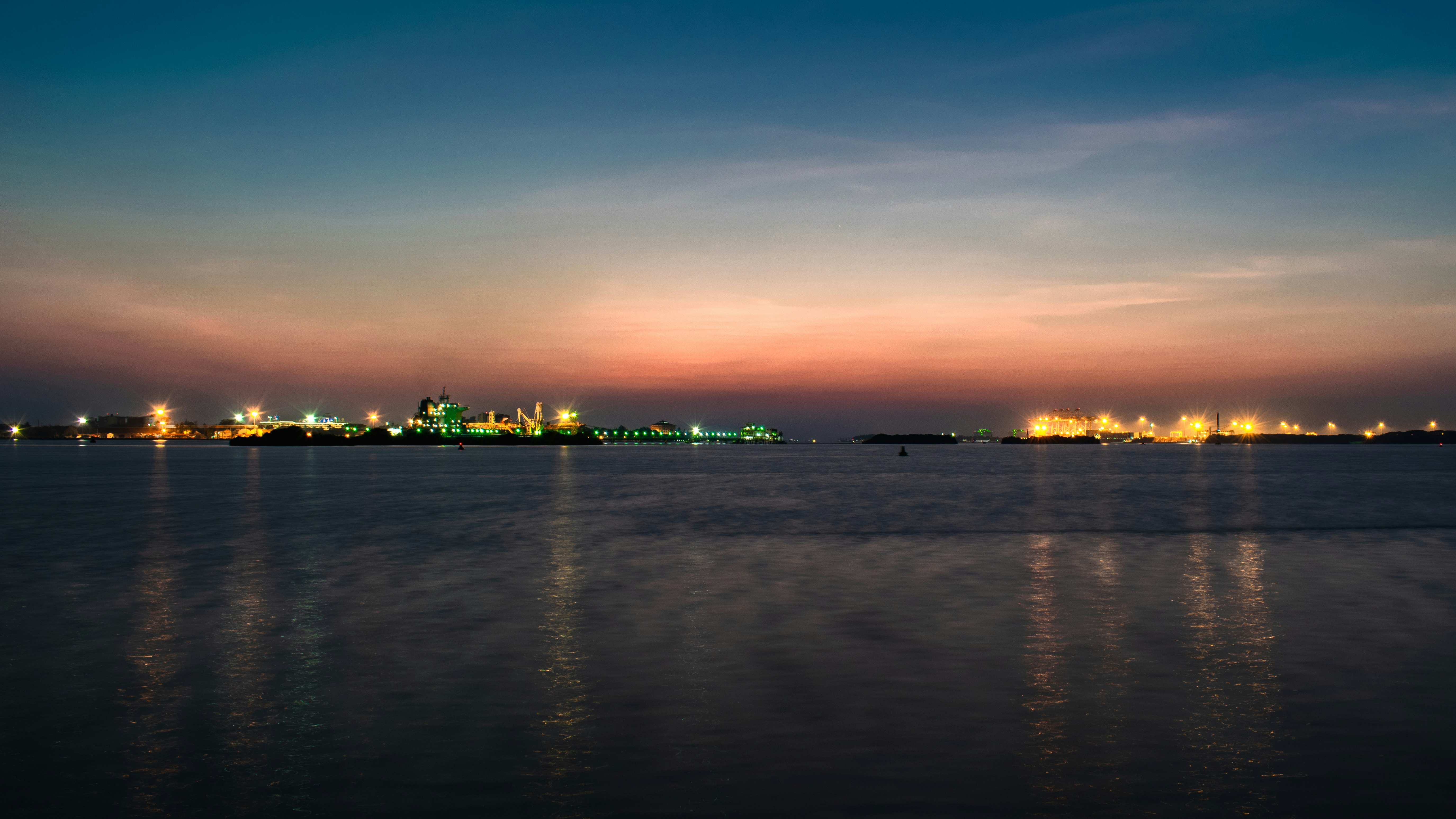 body of water near city buildings during sunset